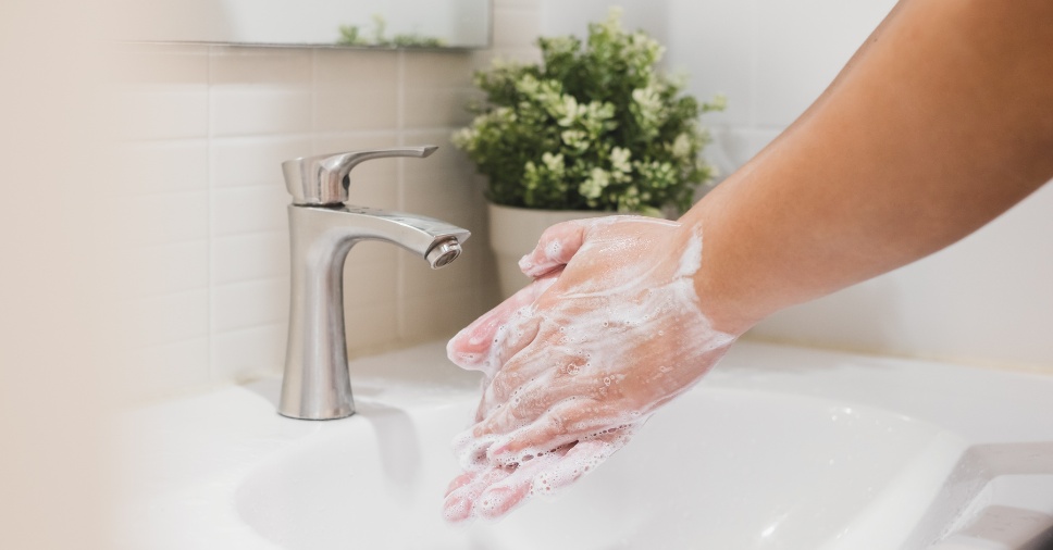 Pessoa lavando as mãos com produtos de higiene na empresa