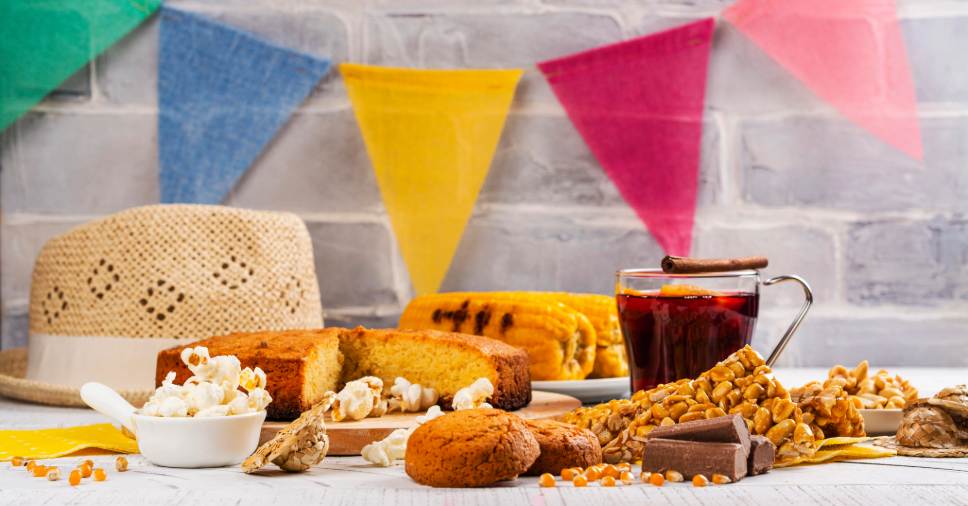 Mesa típica de festa junina corporativa com comidas tradicionais e decoração colorida.