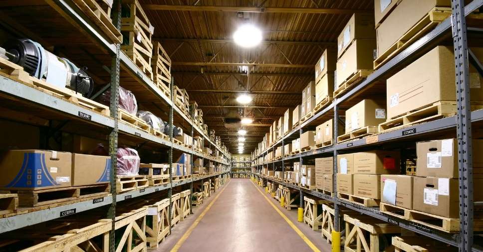 Corredor de um grande armazém com produtos nas prateleiras, ligado à contratação de abastecimento de suprimentos.