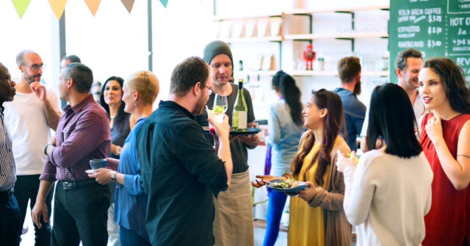 Garçom servindo bebidas em um evento social movimentado exemplifica o uso de mão de obra terceirizada.