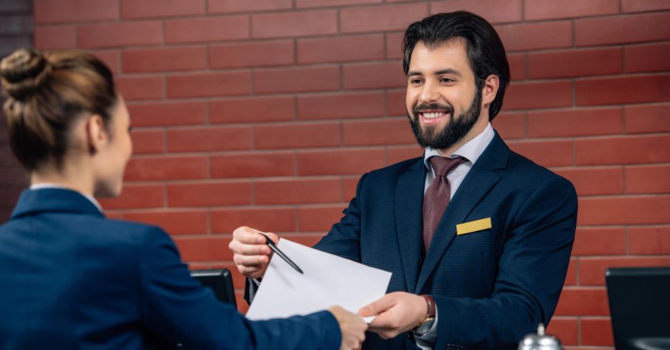 Homem em recepção terceirizada assegura um atendimento profissional a cliente.