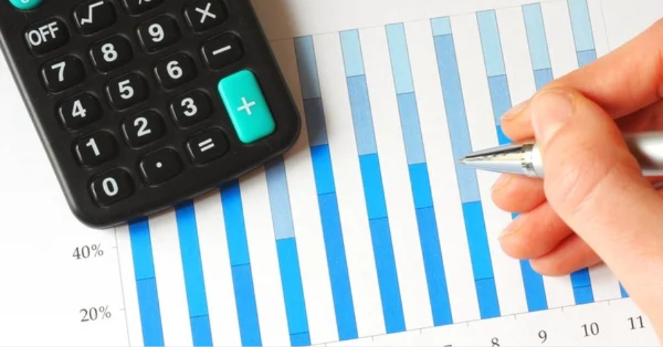 Calculadora e mão com caneta analisam gráfico para um planejamento empresarial eficiente.
